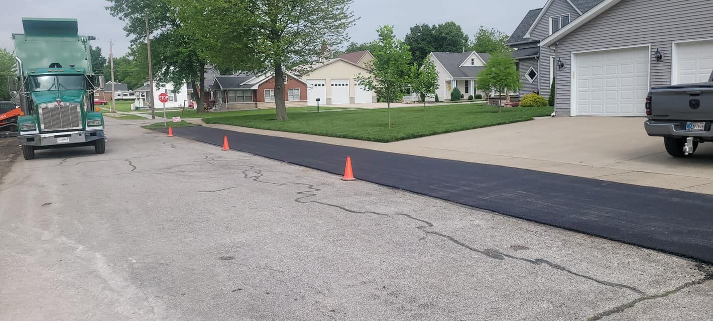 A truck is driving down a road next to a house.