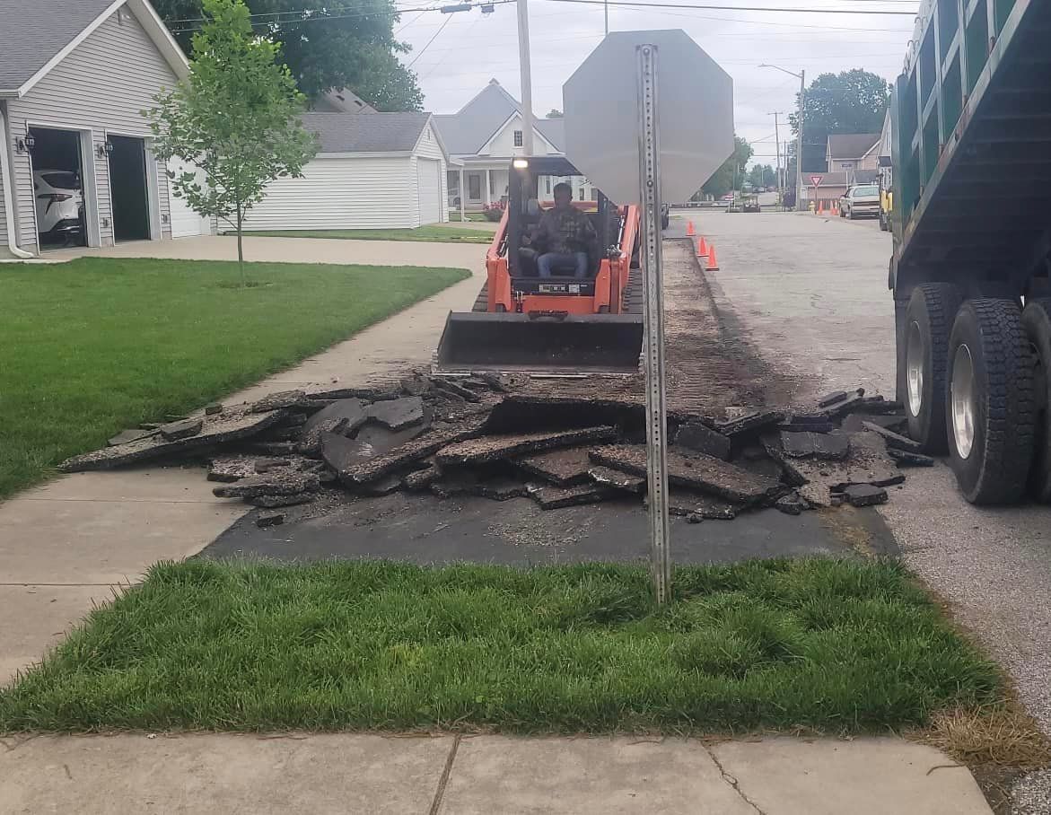 A bulldozer is laying on the sidewalk next to a stop sign