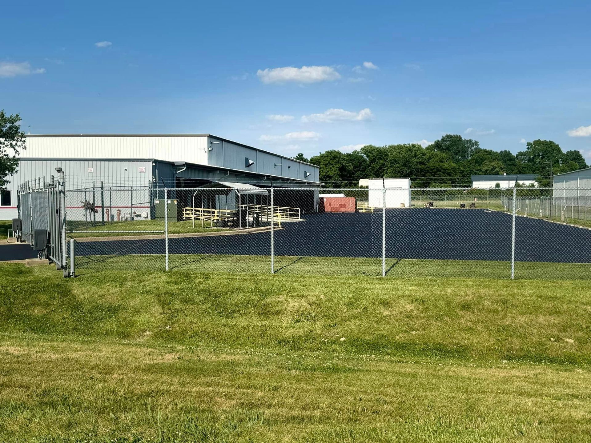 A fence surrounds a field with a building in the background