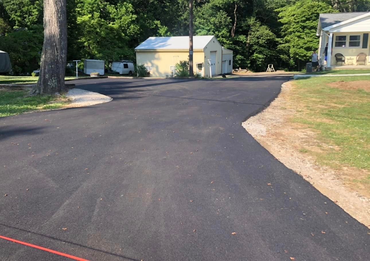 A newly paved driveway with a house in the background.