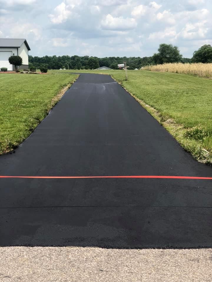 A black driveway with a red line on the side of it leading to a house.