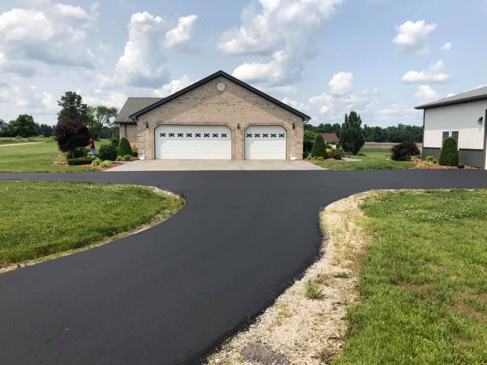 A driveway leading to a house with two garage doors.