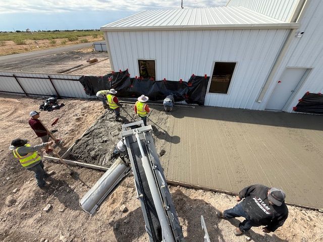 A group of construction workers are working on a concrete driveway
