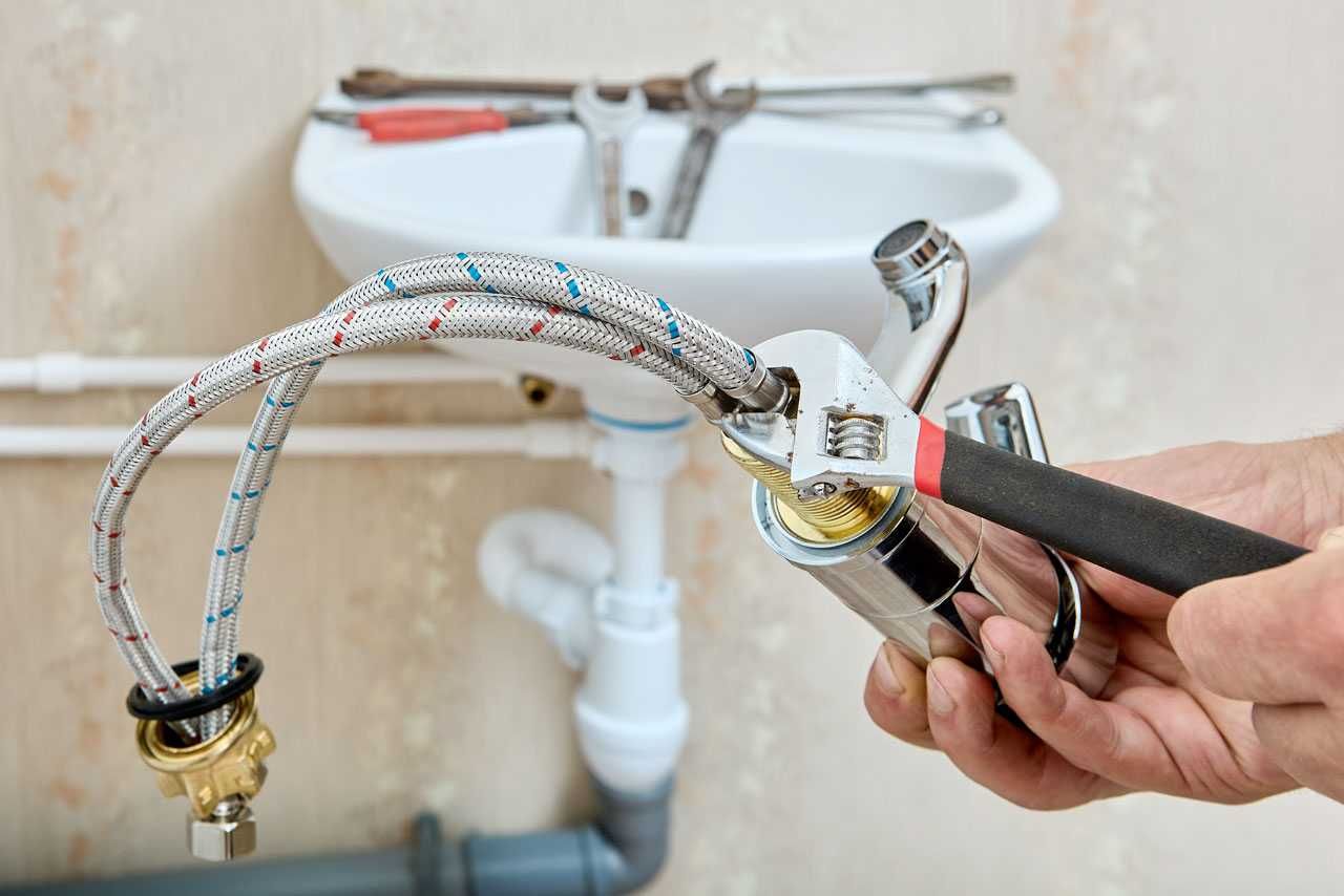 Replacing a flexible sink hose with a wrench under a bathroom sink