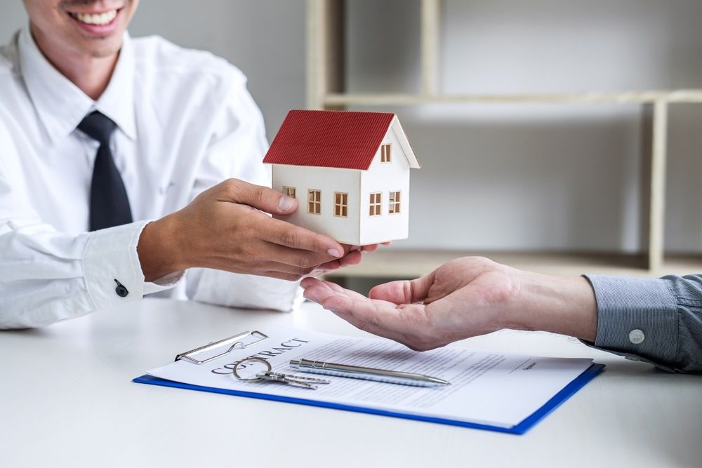 A Man is Giving a Model House to Another Man — Paton Hooke Lawyers & Conveyancers In Taree, NSW