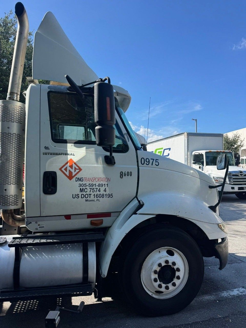White semi-truck parked outdoors on a sunny day. The truck has the word 