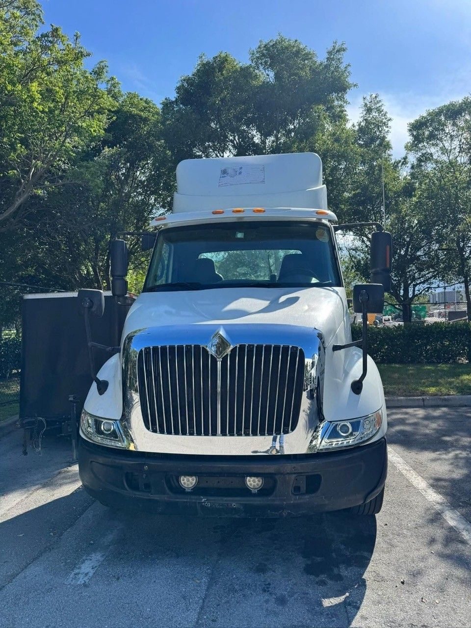 White semi-truck parked outdoors, facing forward. Tall cab, black grille, in a parking lot.