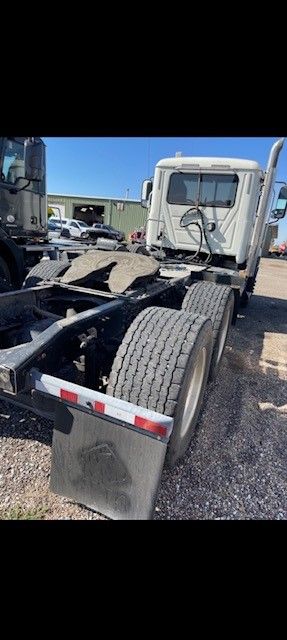 A white semi-truck with dual rear tires parked outside on a sunny day.