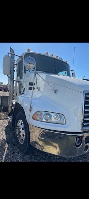 A white semi-truck is parked outside under a bright blue sky.