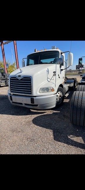 White semi-truck parked outdoors. The truck has a black grill, gray bumper, and large tires.