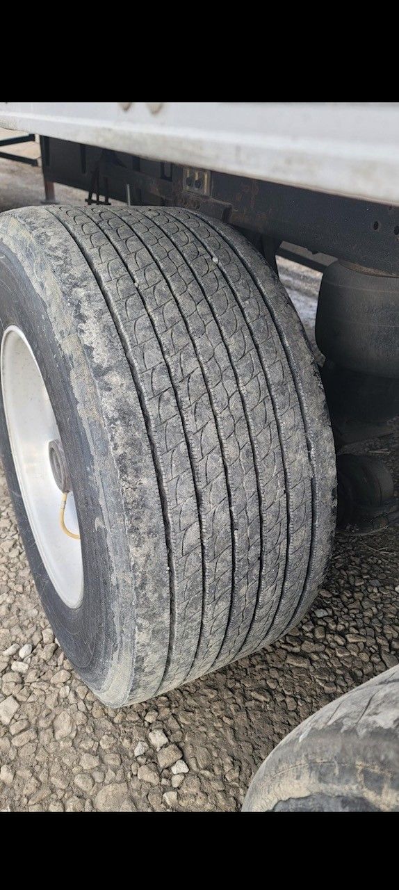 Close-up of a semi-truck tire on gravel ground.