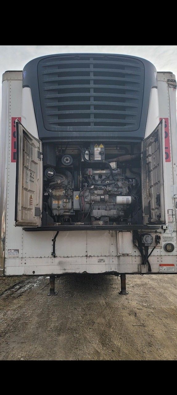Rear of a refrigerated semi-trailer with open doors exposing the engine.