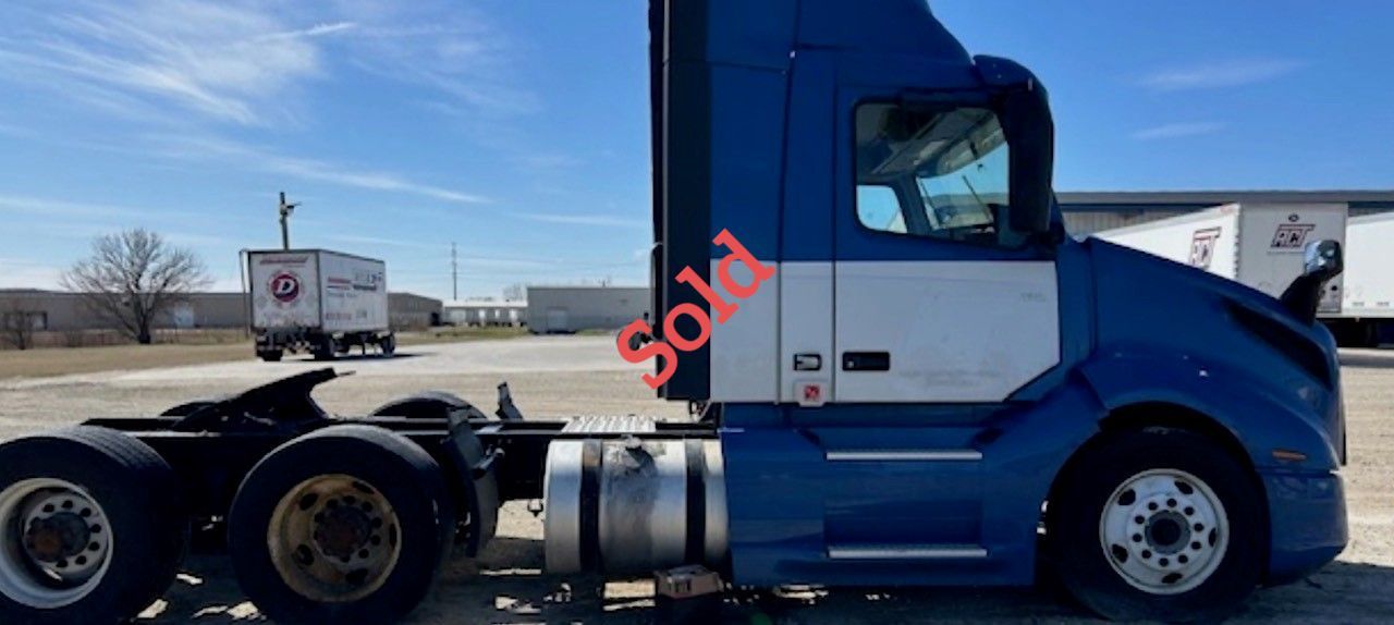 Blue and white semi-truck with “Sold” diagonally across the side.
