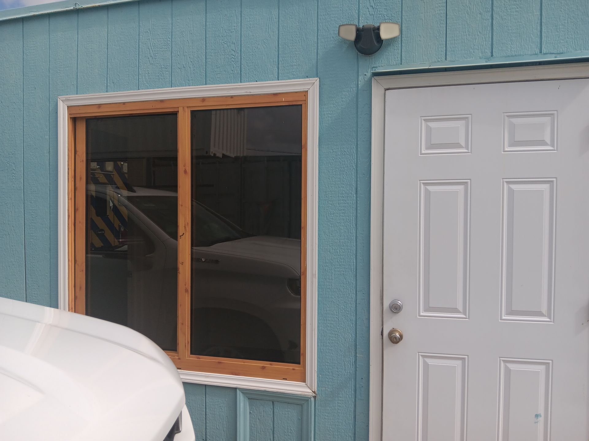 Blue building exterior with a window, a white door, and a security camera.