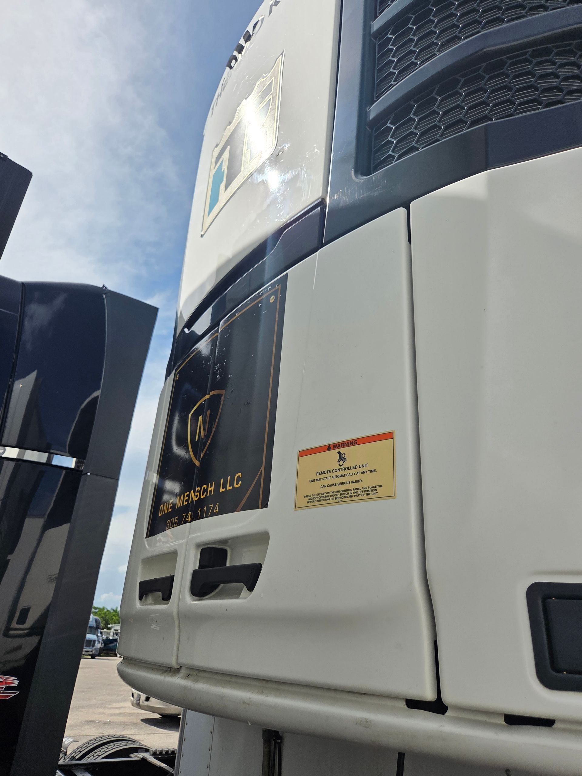 White refrigerated truck unit with black accents and a gold sticker.