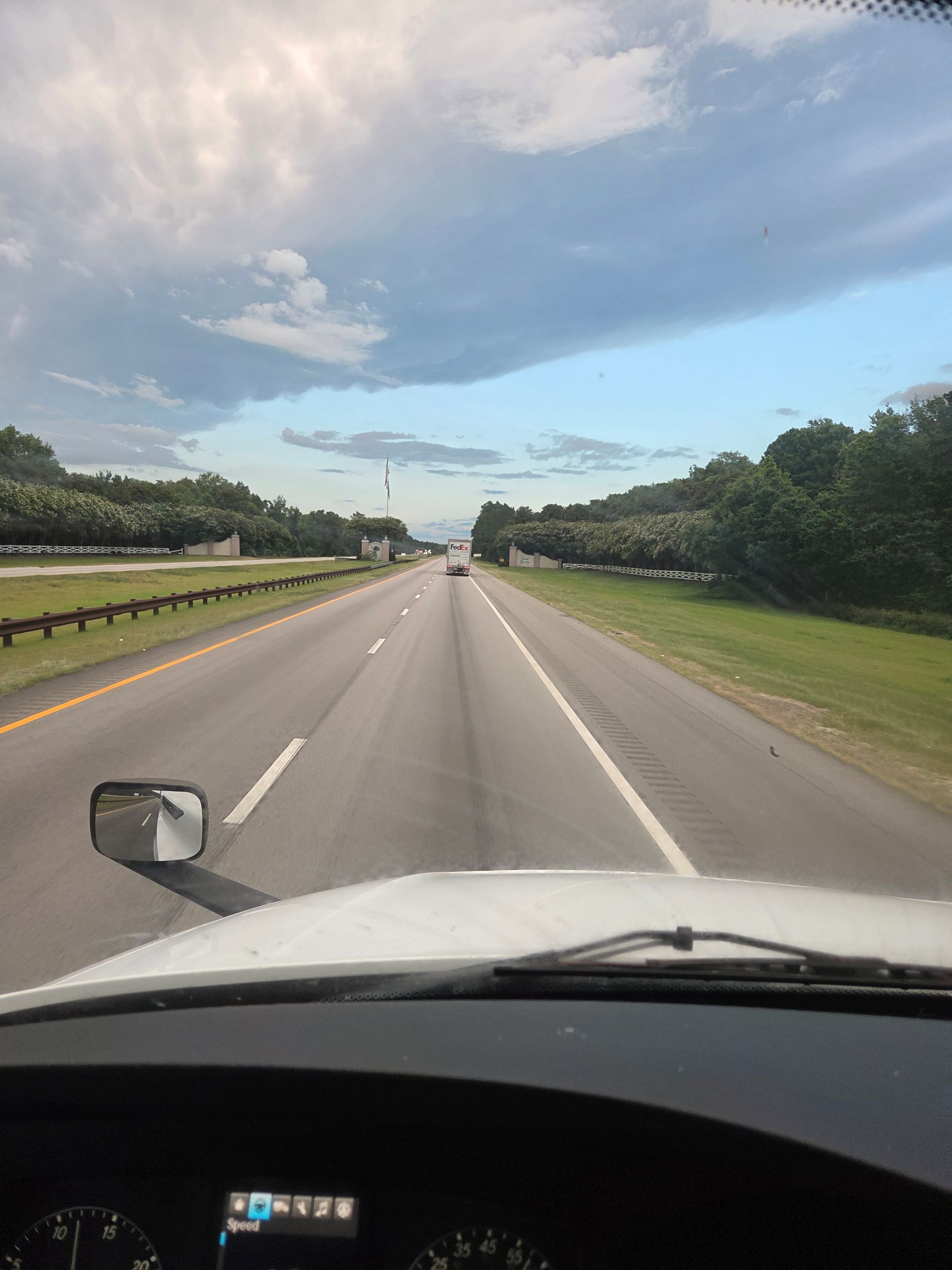 View from a truck cab, driving on a highway, bright sky.