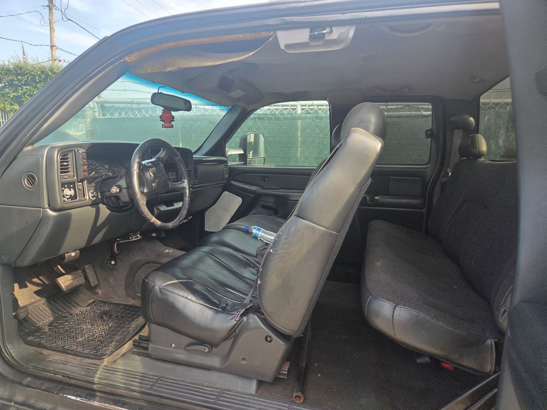 Interior of a black pickup truck. Driver's seat reclined, back seat visible. Dirty floor mats.