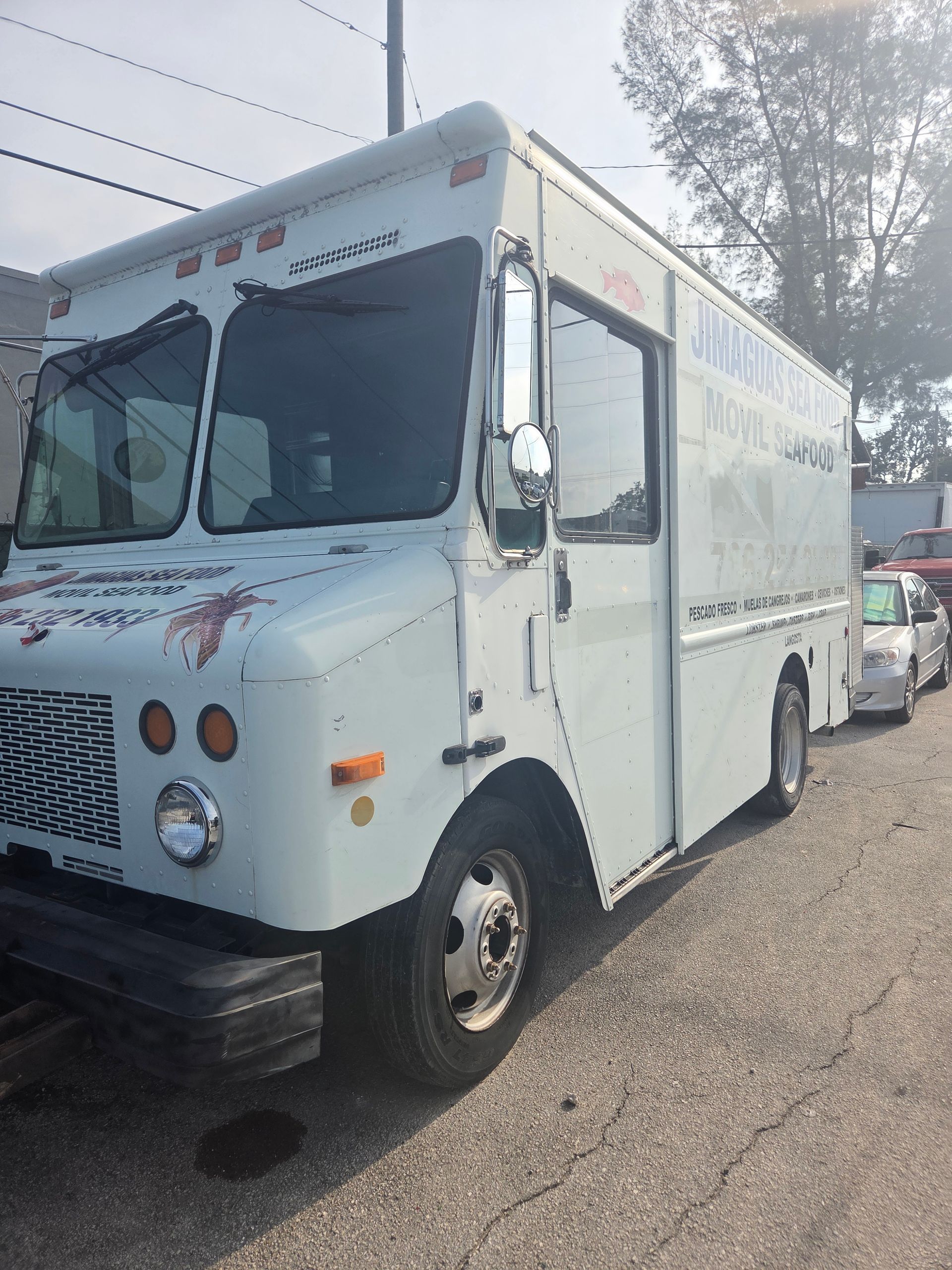 White delivery truck parked on a paved lot, sunny day.