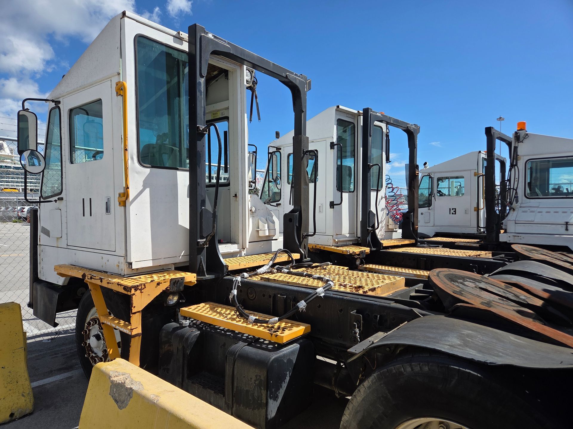 White and black yard trucks parked outdoors on a sunny day.