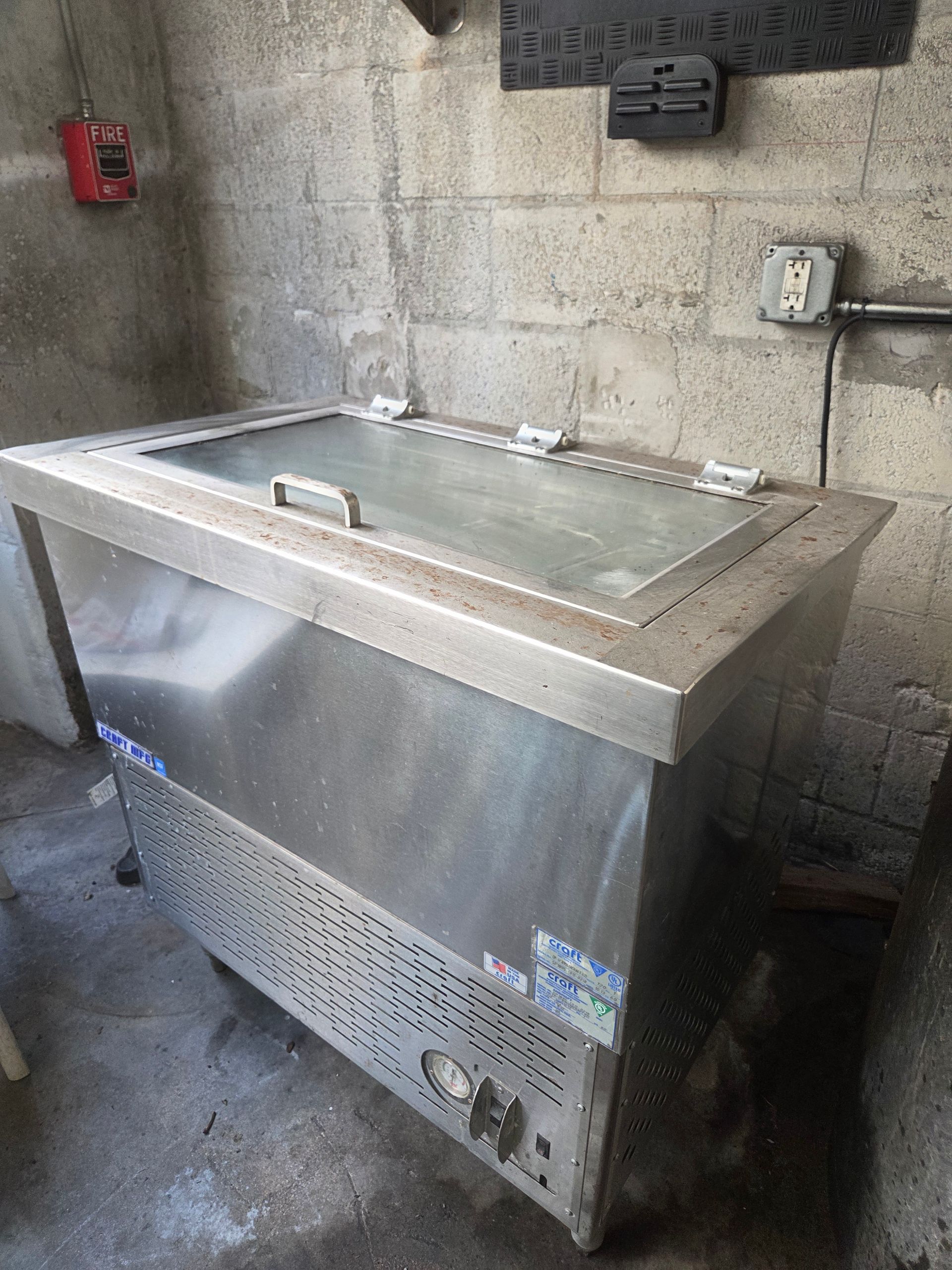 Stainless steel ice cream freezer in a cinder block room.