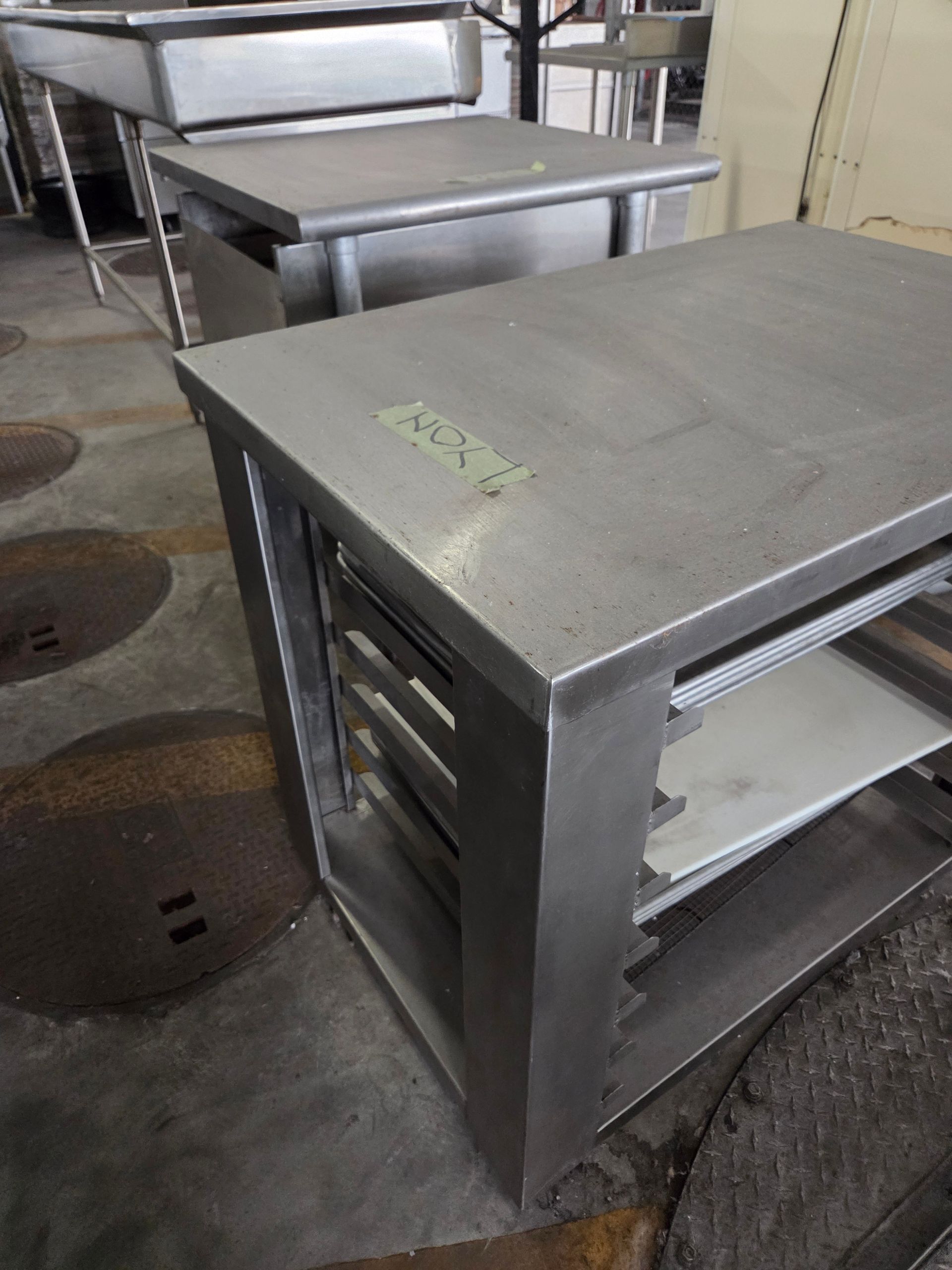 Stainless steel commercial kitchen work tables with shelves.