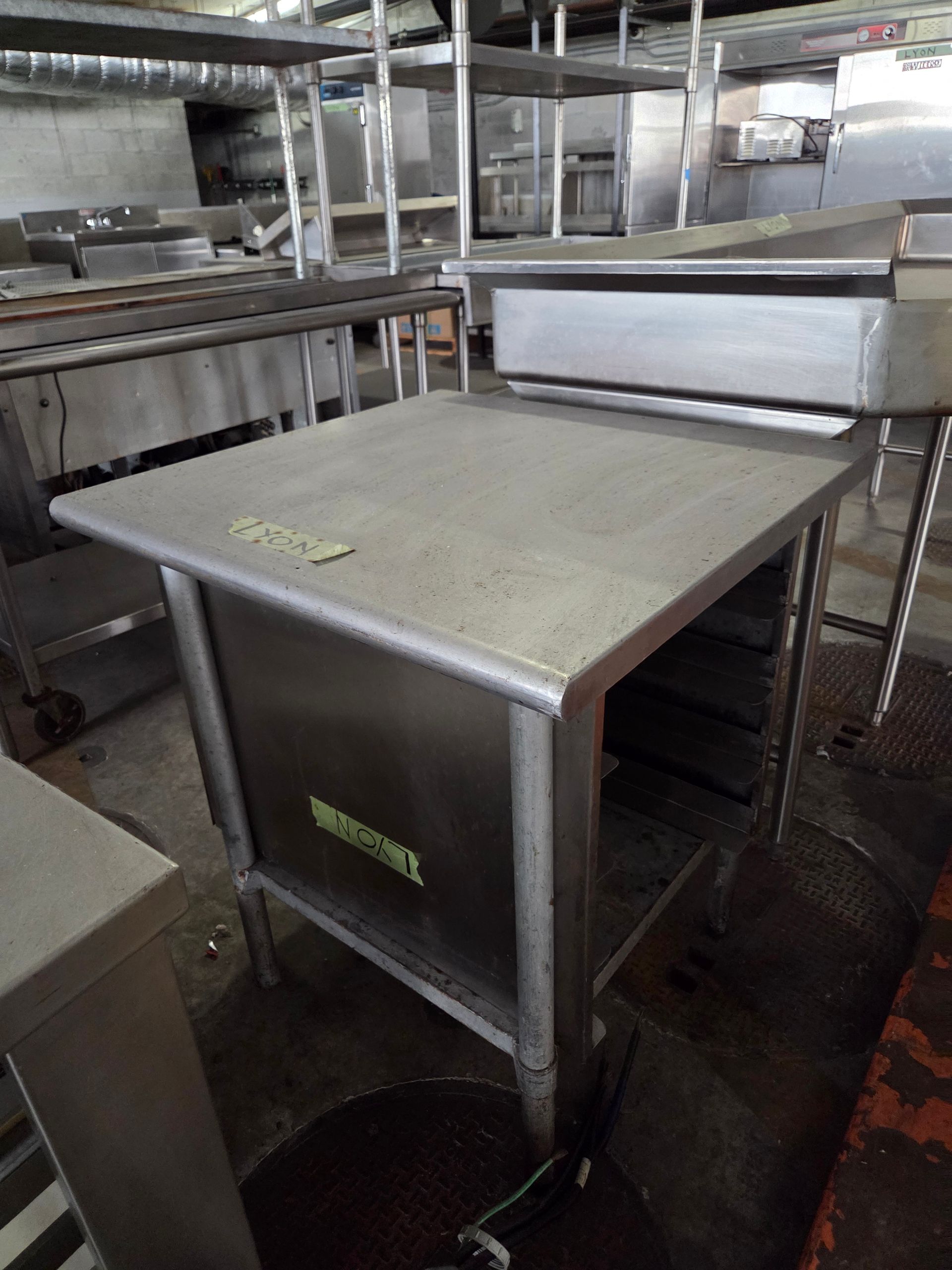 Stainless steel prep table in a commercial kitchen with other equipment.