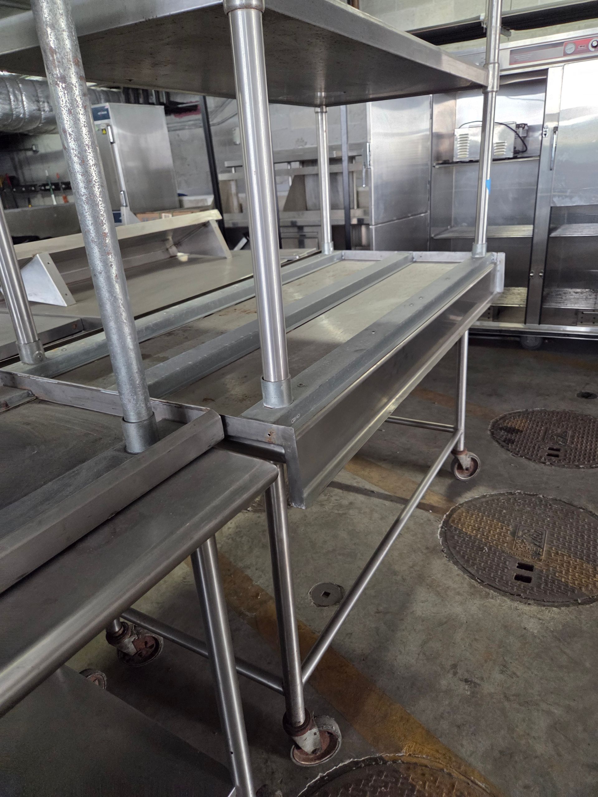 Stainless steel shelving unit on wheels in a commercial kitchen setting.