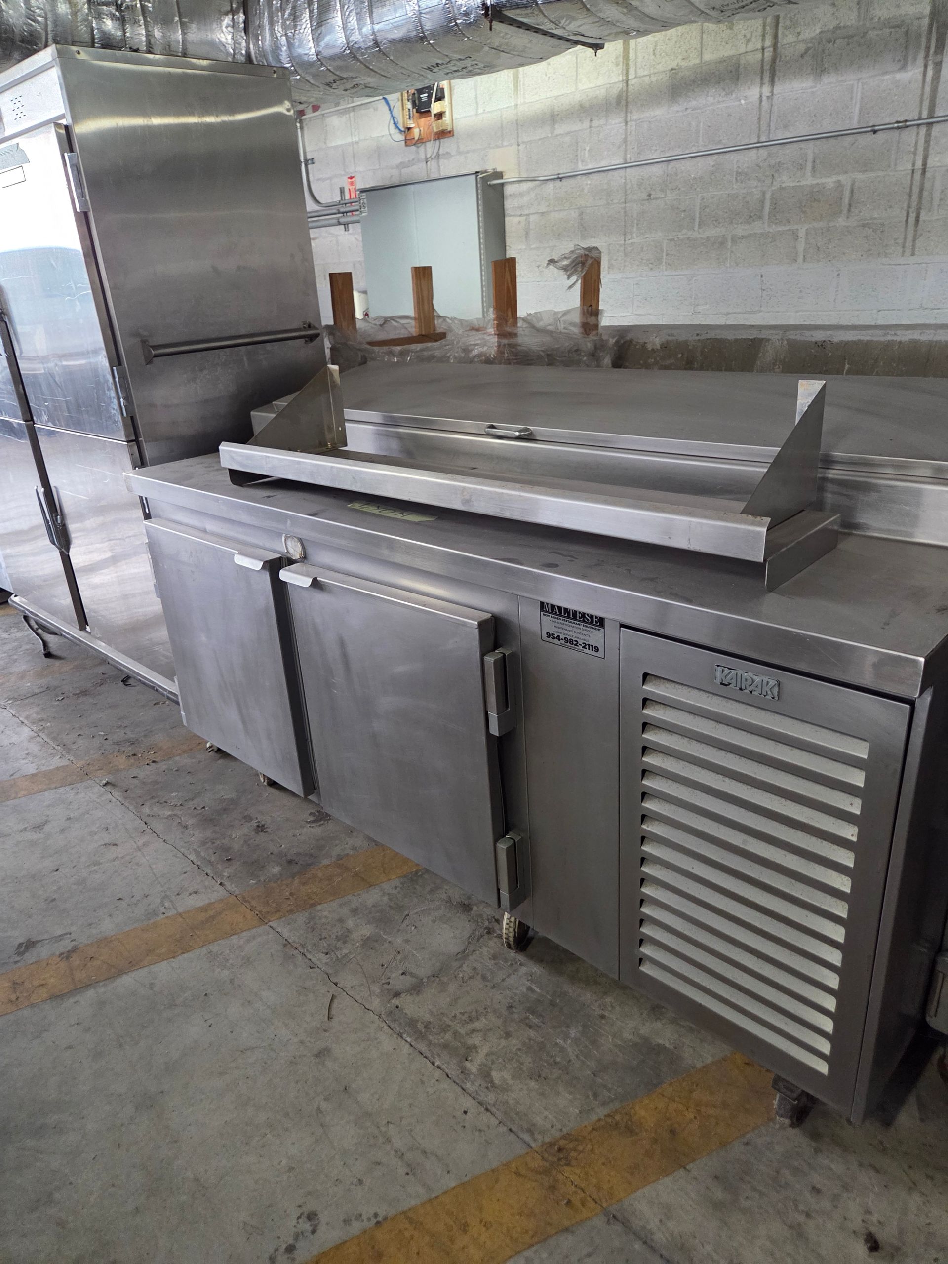 Stainless steel commercial refrigeration unit in a warehouse.