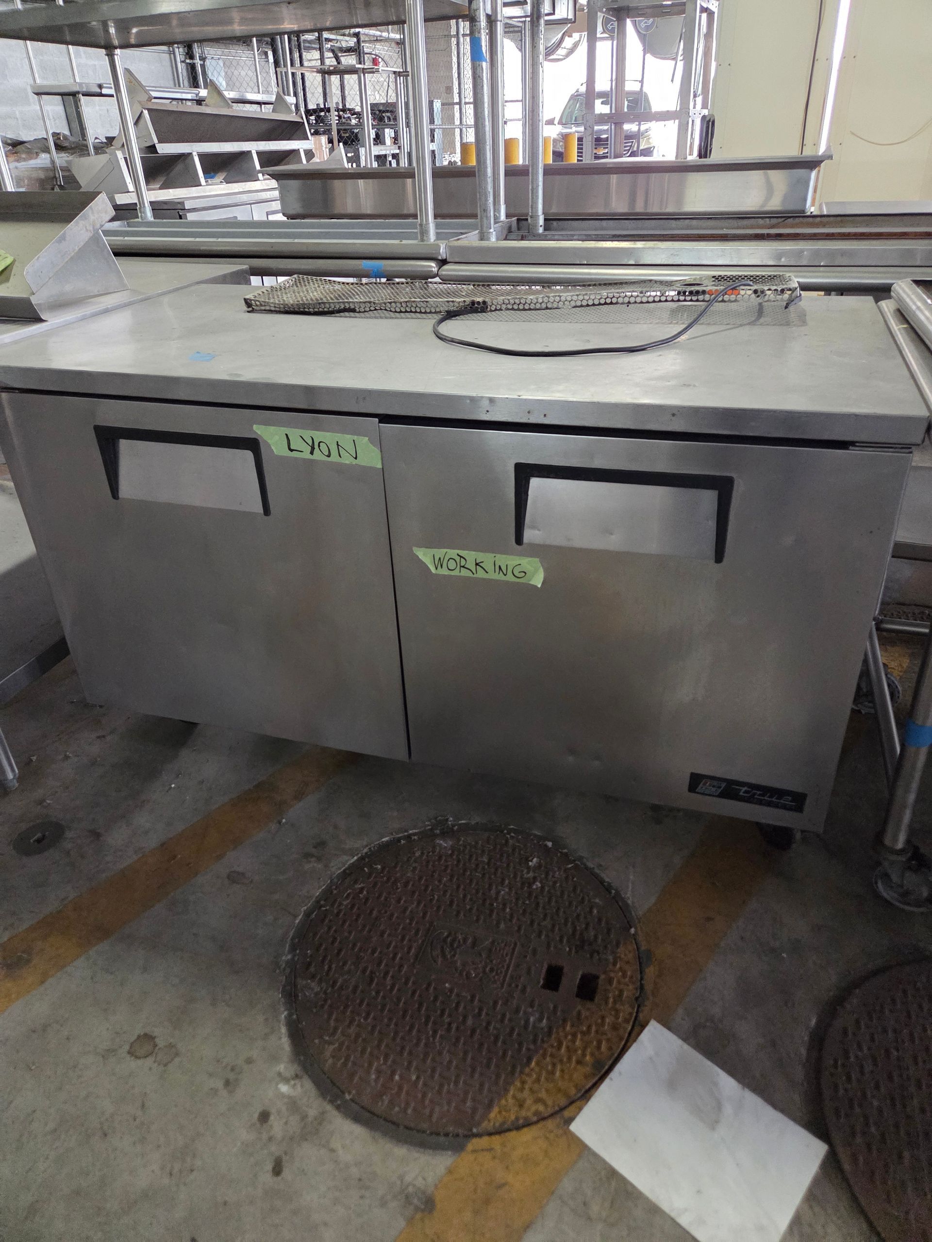 Stainless steel refrigerator in a commercial kitchen with two doors.