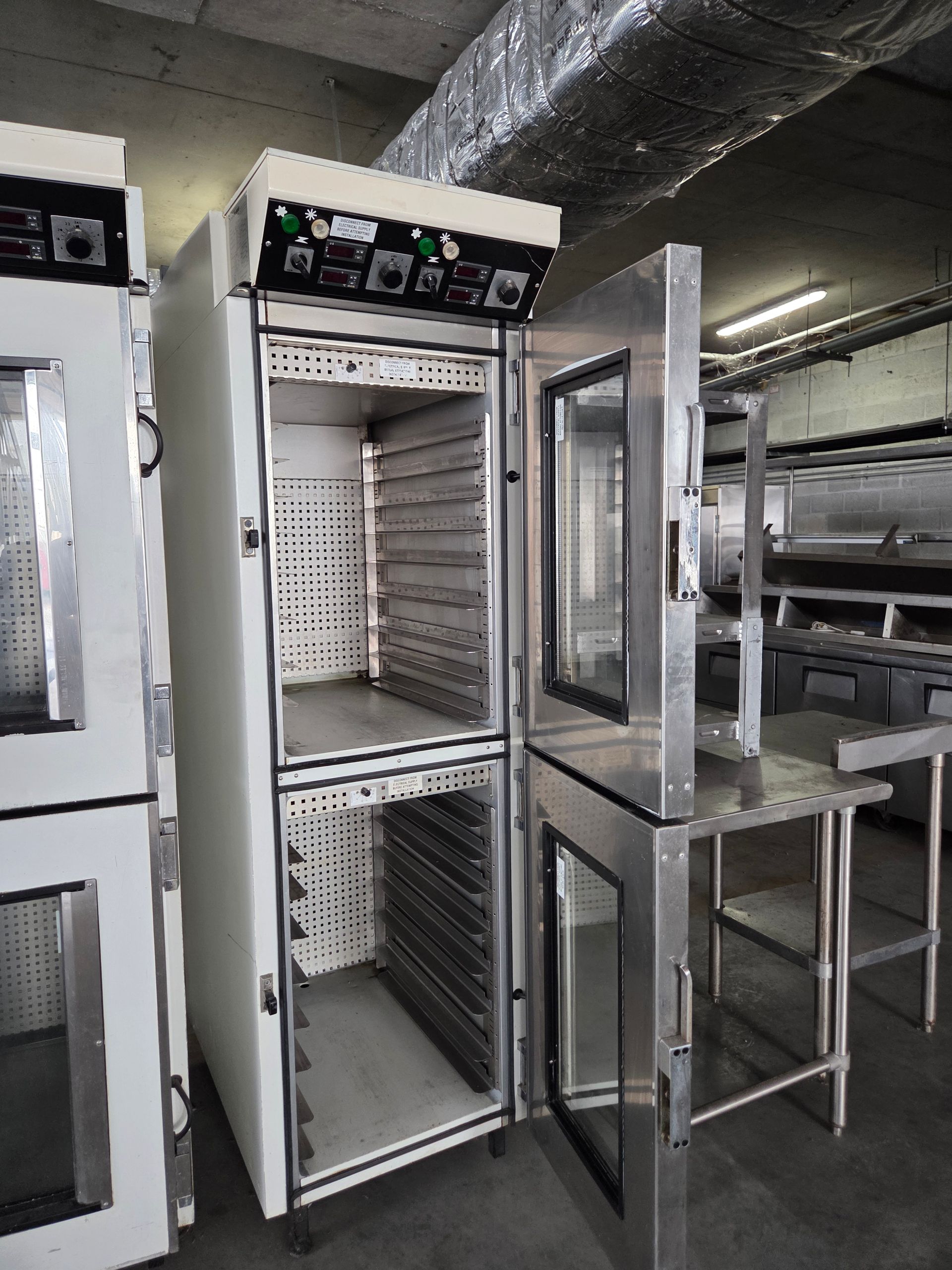Commercial oven with open doors, stainless steel and white, in a kitchen setting.