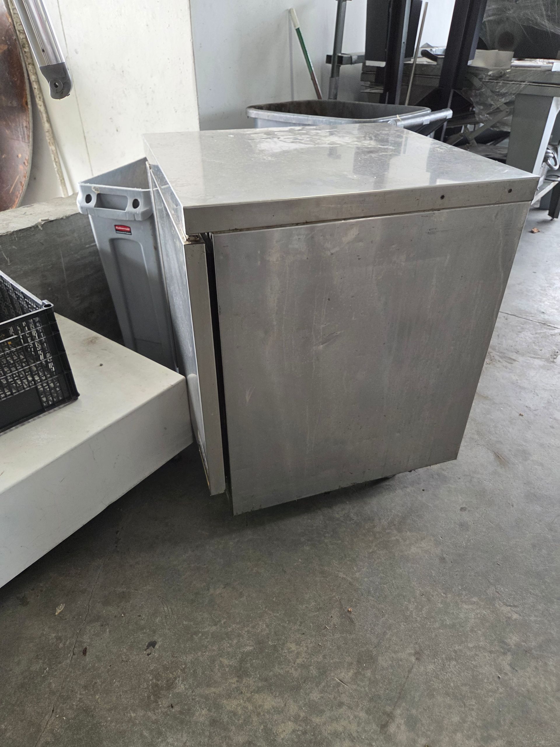 Stainless steel cabinet with a closed door, resting on a concrete floor.