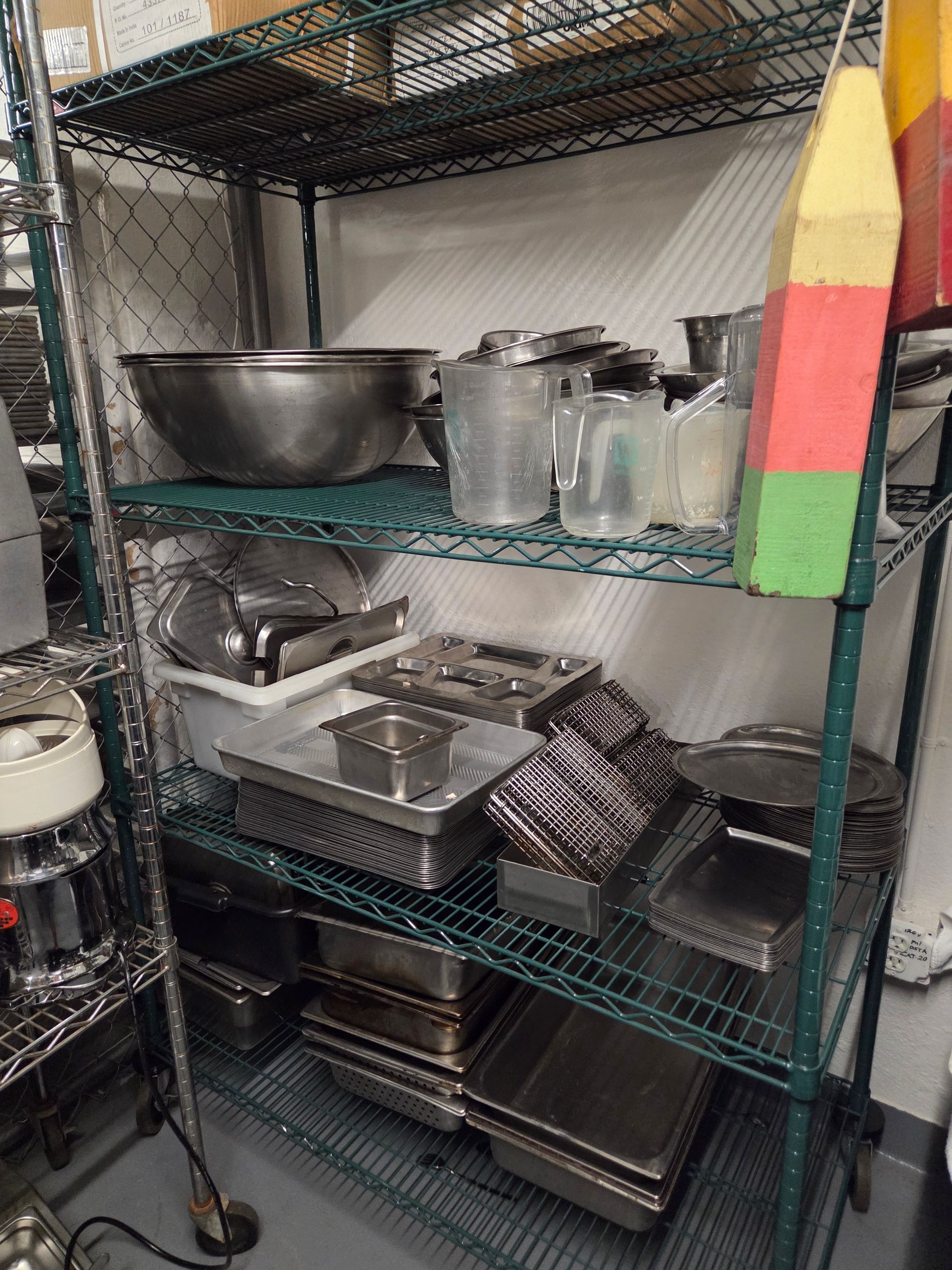 Wire shelving unit holding various kitchen tools and containers.