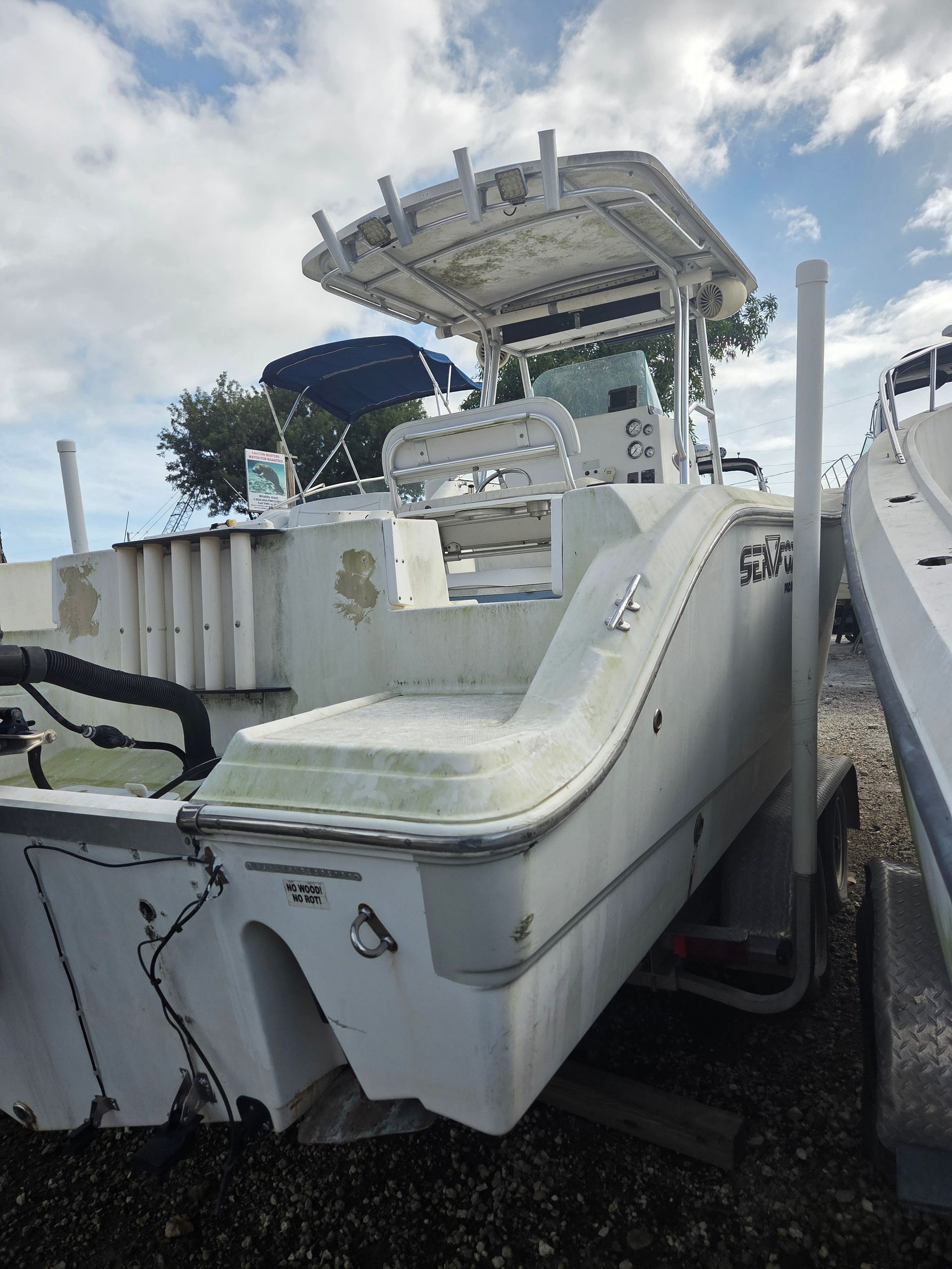 White fishing boat on trailer, blue accents, cloudy sky backdrop.