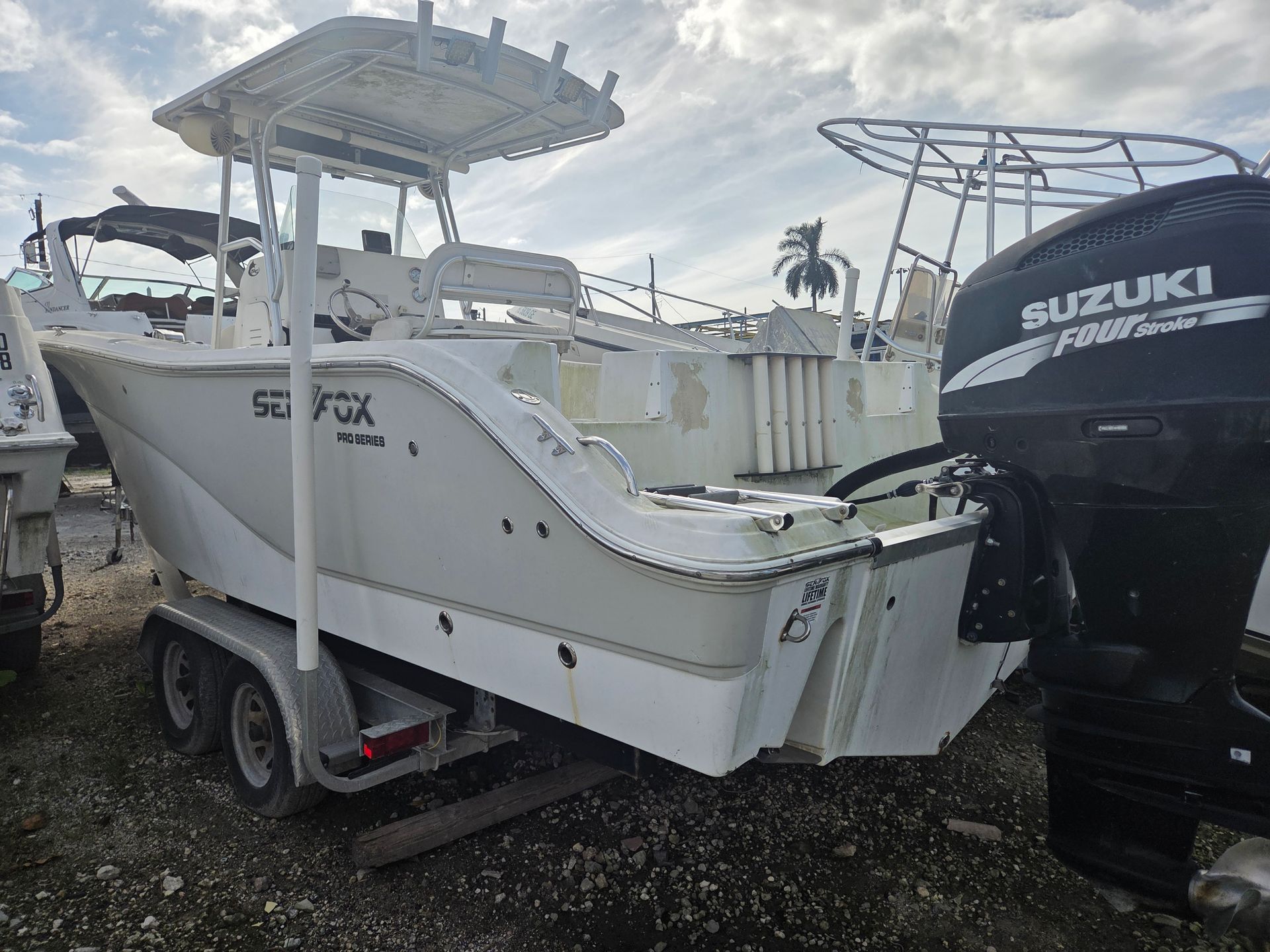 White Sea Fox boat on a trailer, with a Suzuki outboard motor, under a cloudy sky.