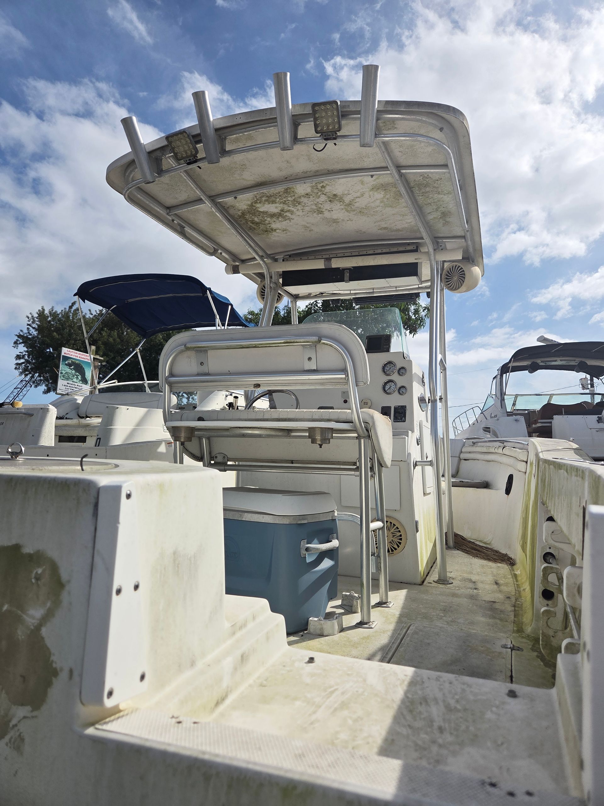 White fishing boat deck, metal canopy and seating. Boat docked outdoors, clear sky.