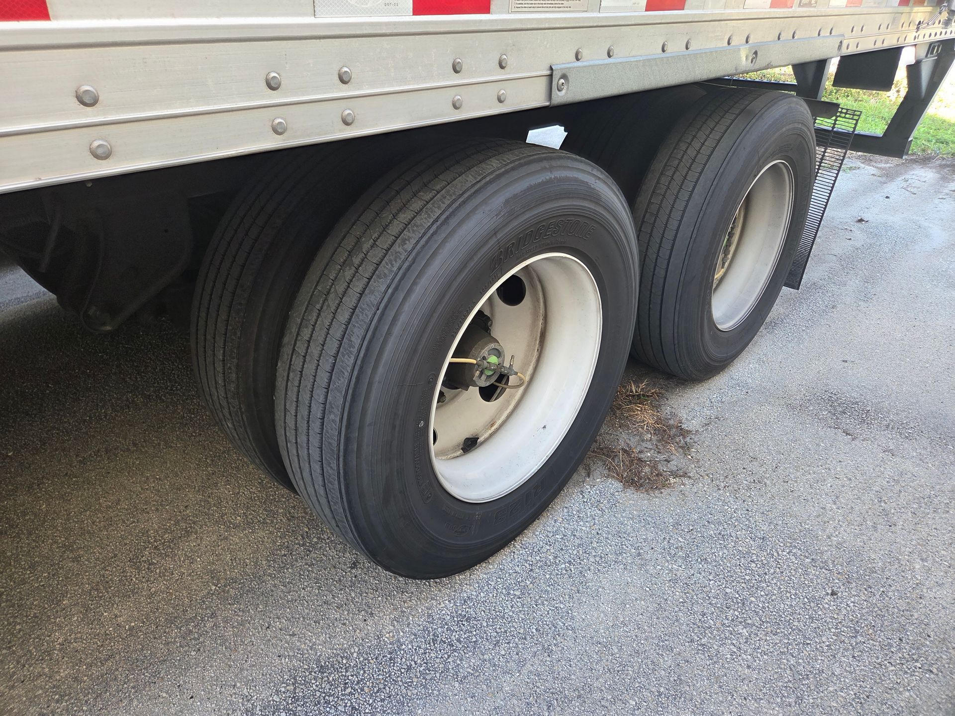Tandem trailer tires on a semi-truck; the tires are black, and the rims are white.