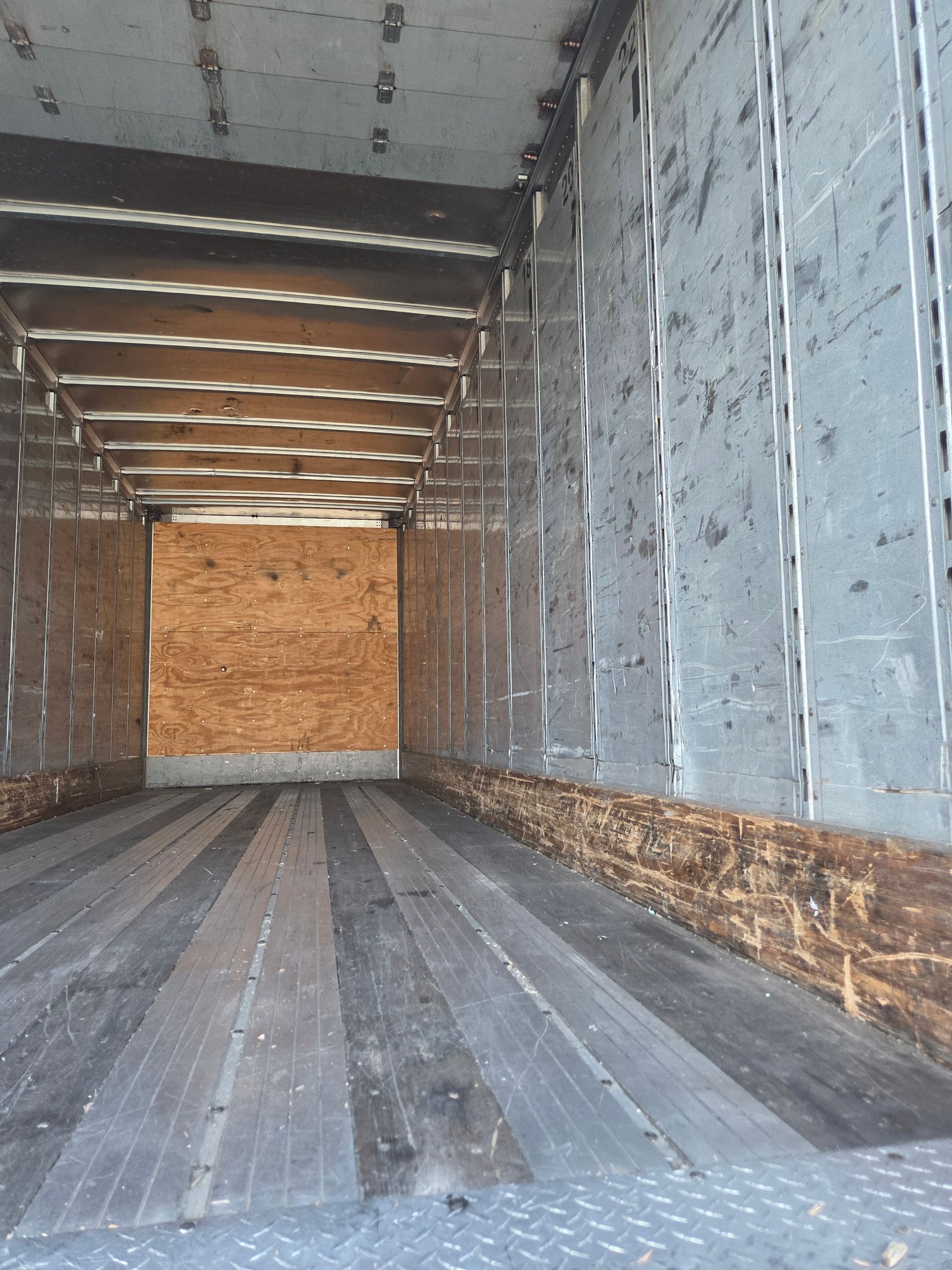 Interior of an empty truck cargo area, with wooden floor and walls.