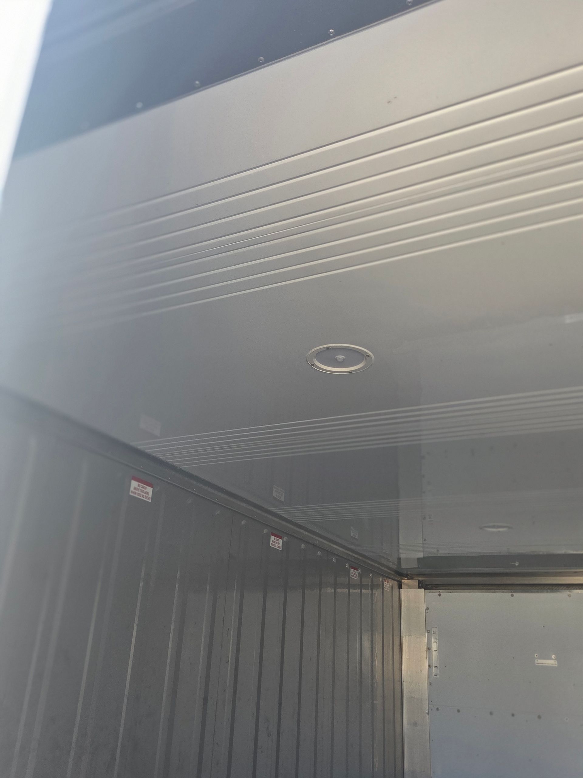 Interior view of a gray shipping container with a light fixture on the ceiling.