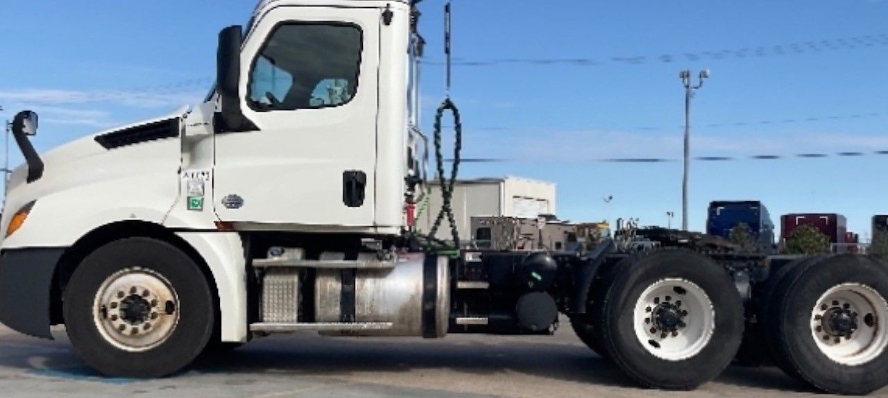 White semi-truck parked outdoors under a blue sky.