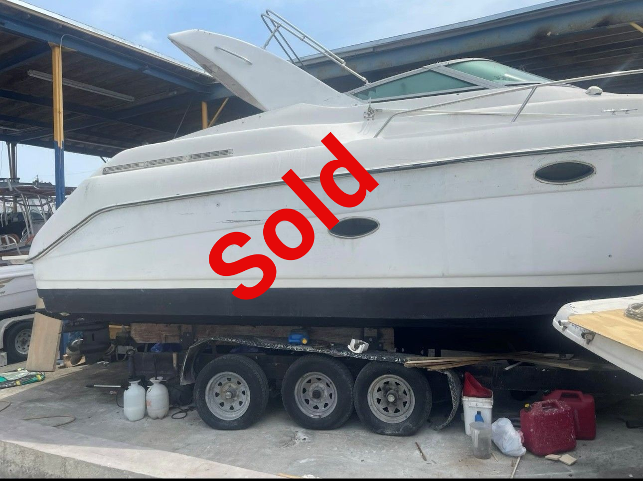 White motorboat on a trailer, under a shelter.