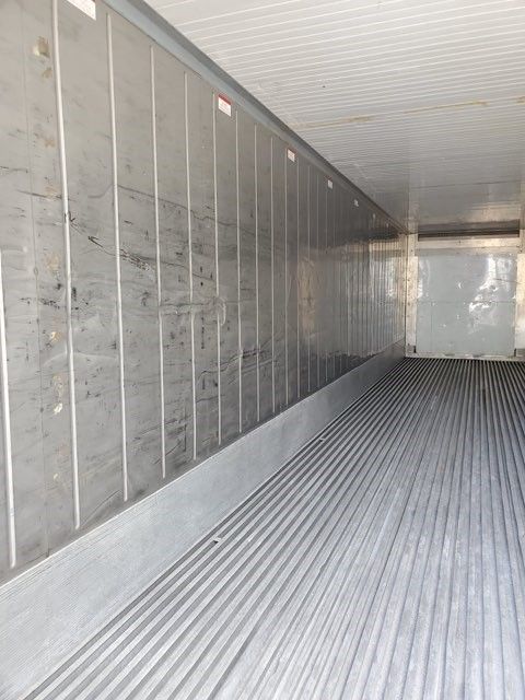 Interior of a refrigerated truck trailer with ribbed metal floor and walls.