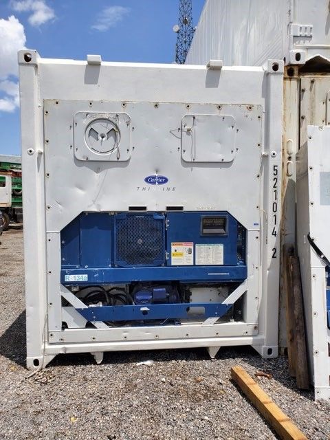 Refrigerated shipping container with white exterior and blue machinery, parked outdoors.