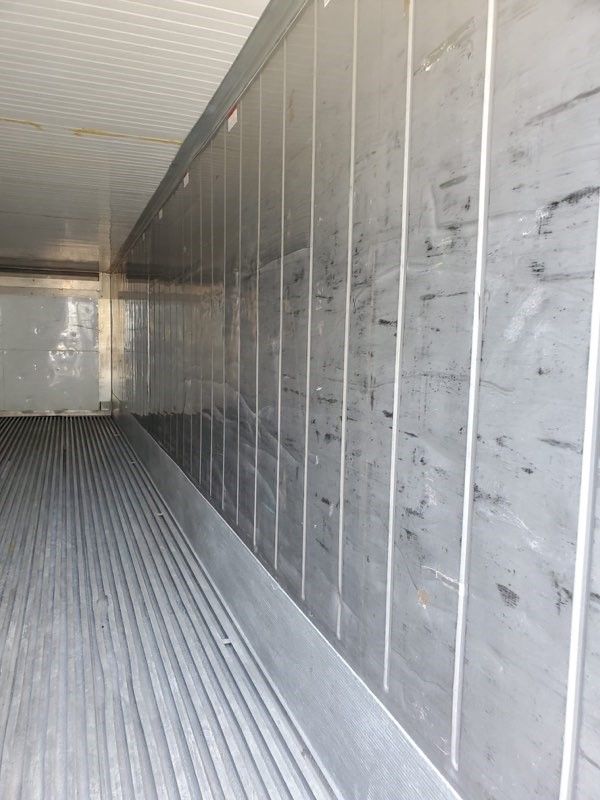 Interior of a refrigerated truck trailer, showing corrugated floor and vertical wall panels.