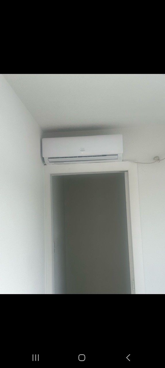 Air conditioning unit mounted on a white wall above a doorway.