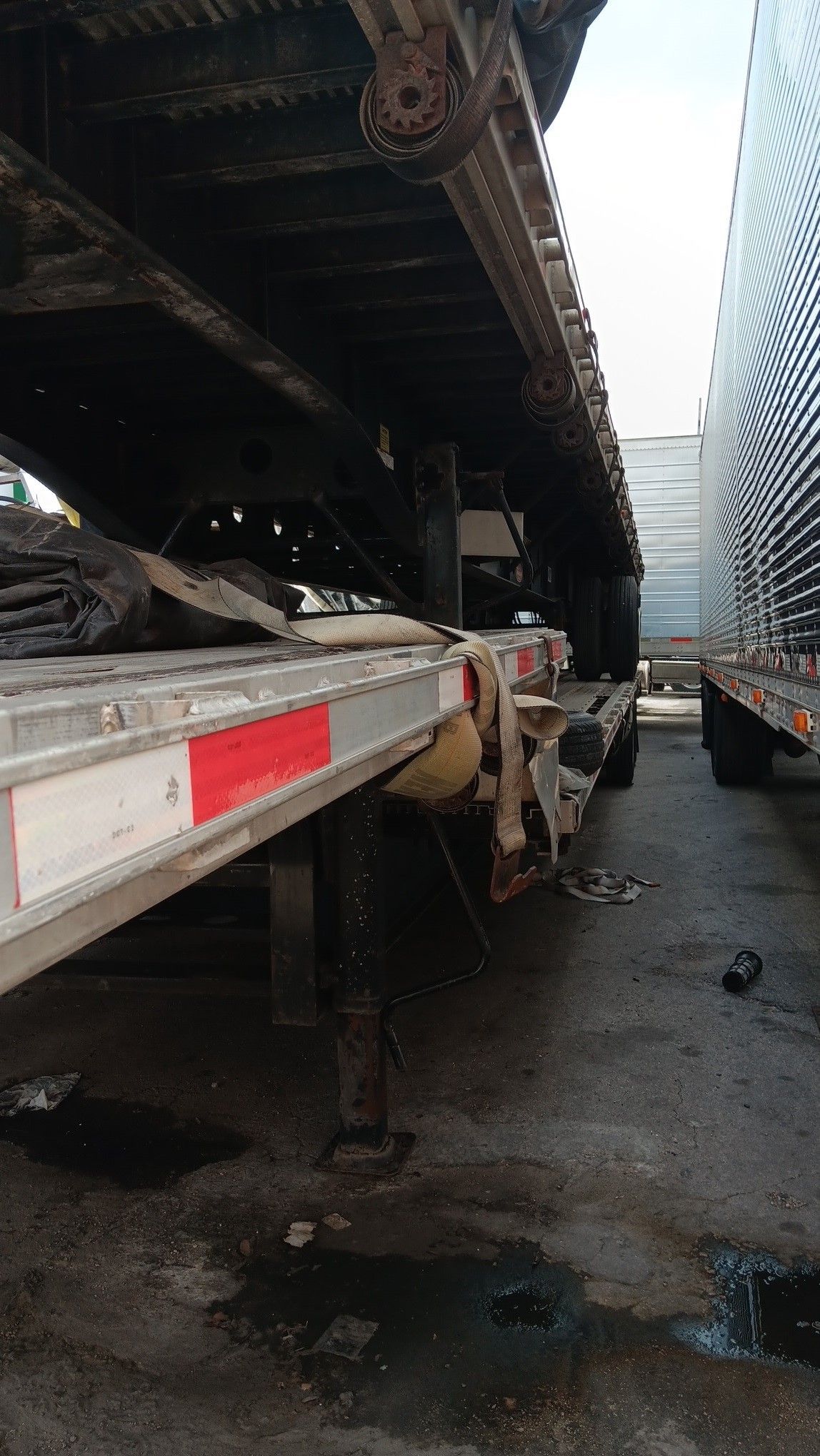 Damaged semi-trailer with red and white reflectors. Black soot covers the underside.
