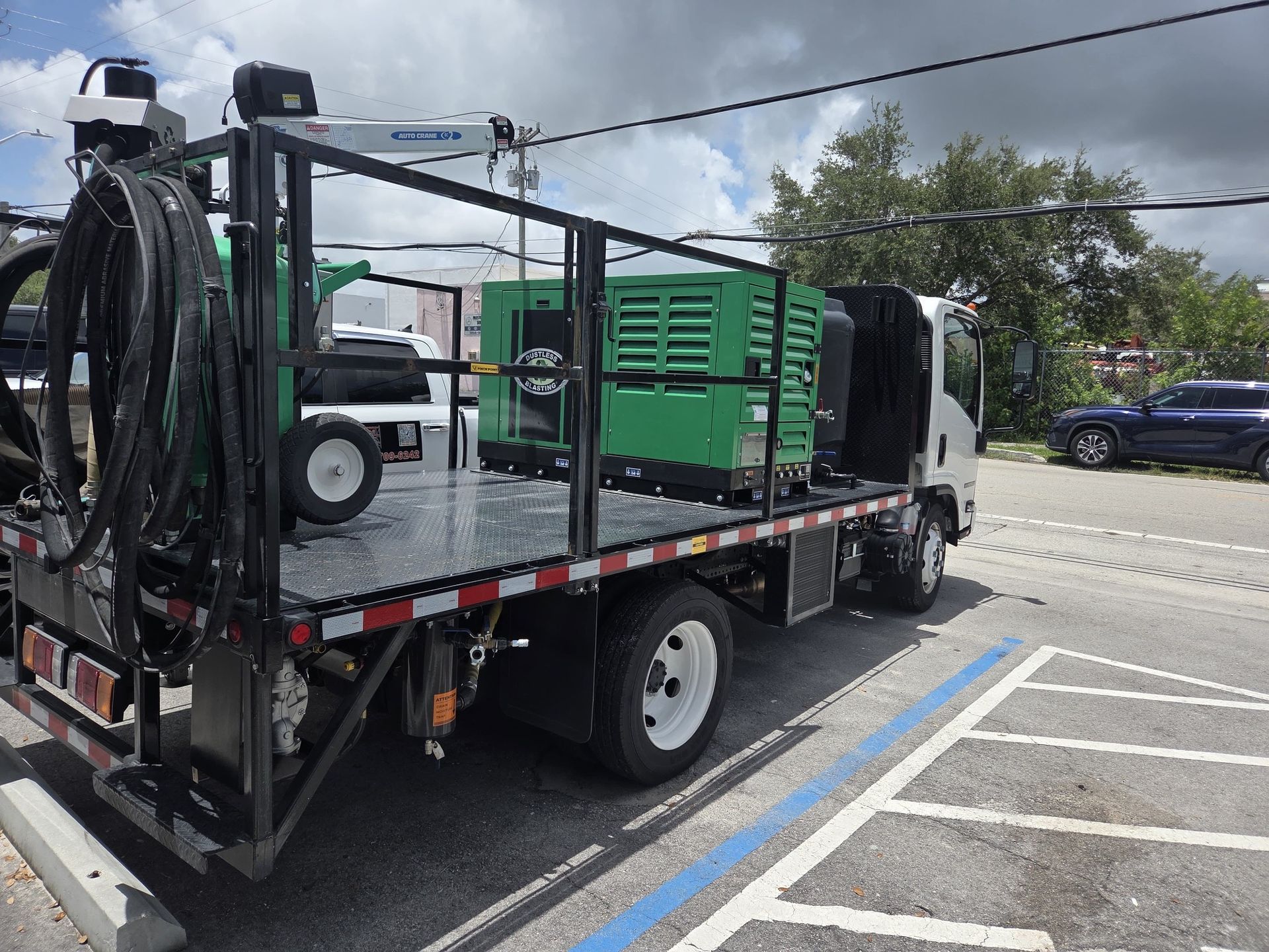 Truck bed with green generator, black equipment, and hose reels parked outdoors.
