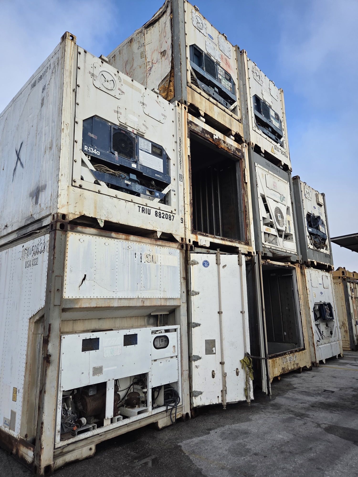 Stacked, weathered white refrigerated shipping containers.