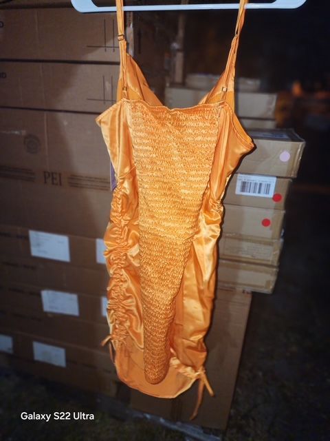 Orange satin dress hanging in front of cardboard boxes.