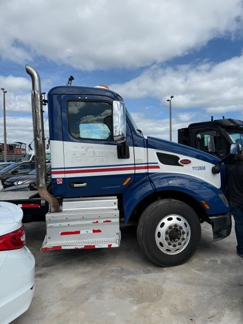 Blue and white tow truck parked outside on a cloudy day.