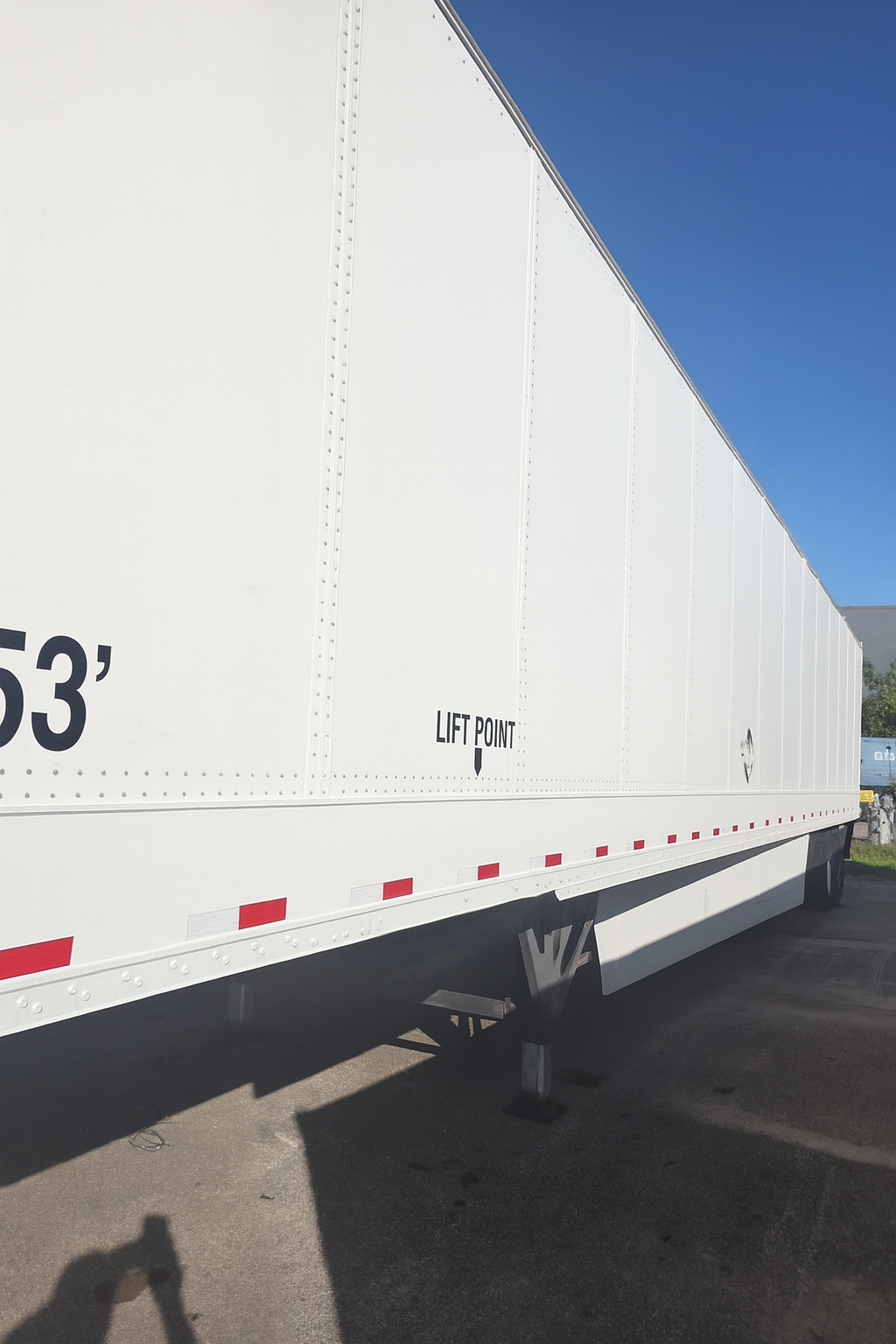 White semi-trailer against a blue sky, marked 53 feet.